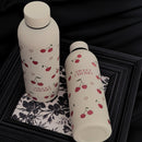 Femme tenant la gourde Cery 500 ml beige avec motifs cerise et cœur.