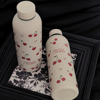 Femme tenant la gourde Cery 500 ml beige avec motifs cerise et cœur.