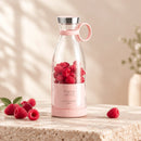 Mini mixeur RENA rose rempli de fraises, avec boisson et fruits à côté